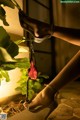 A woman's legs in high heels with a rose hanging from a plant.