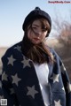 A woman wearing a black hat and a blue and white blanket.