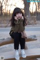 A little girl sitting on a wooden bench in a park.