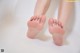 A close up of a person's bare feet on a white surface.