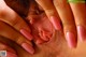 A close up of a woman's hands with pink fingernails.