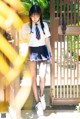 A woman in a school uniform is standing in front of a gate.