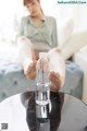 A woman sitting on a couch with her feet in a bottle of water.