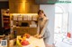 A woman standing in a kitchen next to a counter with a plate of fruit.