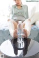 A woman sitting on a couch with her feet up next to a bottle of water.