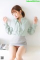 a woman in a green shirt and skirt sitting on a white table