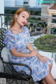 A woman sitting on a bench in a blue dress.