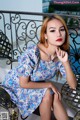 A woman sitting on a bench wearing a blue dress.