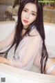 A woman with long black hair sitting in a bathtub.