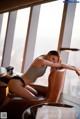 A woman sitting in a chair in front of a window.