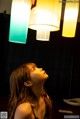 A woman looking up at three lamps hanging from the ceiling.