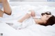 A woman laying on a bed in a white shirt.