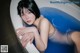 A woman laying in a bathtub with blue water.