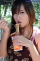 A woman eating a bowl of noodles with a fork.