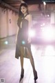 A woman in a black dress standing in a parking garage.