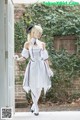 A woman in a white dress is standing in front of a door.