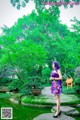 A woman in a purple dress standing next to a pond.