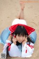 A woman in a white and red dress laying on the sand.