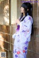 A woman in a kimono leaning against a wooden wall.