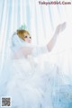 A woman in a wedding dress sitting next to a bird cage.