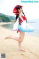 A woman in a red and white outfit is standing on a beach.