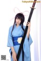 A woman in a blue kimono holding a sword.