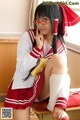 A woman in a school uniform sitting on a desk.