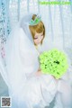 A woman in a wedding dress sitting on a swing holding a bouquet of flowers.