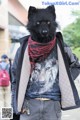 A man wearing a black wolf mask and a red scarf.