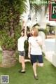 A couple of women standing next to each other near a palm tree.