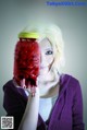 A woman holding a mason jar filled with blood.