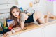 A woman laying on top of a kitchen counter next to a sink.