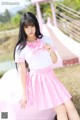 A woman in a pink and white uniform posing for a picture.