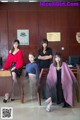 A group of women sitting on a chair in front of a desk.