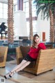 A woman sitting on a wicker chair in a lobby.