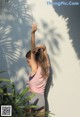 A woman standing in front of a white wall with a palm tree.