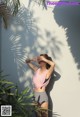 A woman standing in front of a white wall with a palm tree.