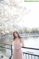 A woman in a pink dress standing next to a body of water.