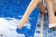 A woman's feet in a swimming pool with water splashing on them.