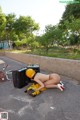 A woman laying on the ground next to a suitcase.