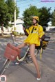 A woman in a yellow raincoat is riding a bike.