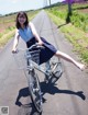 A woman riding a bike down a road with her legs in the air.