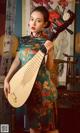 A woman in a cheongsam holding a musical instrument.