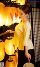 A woman standing in front of a bunch of yellow lanterns.