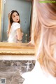 A woman standing in front of a mirror in a bathroom.