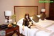 A woman sitting on a bed in a hotel room.