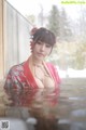 A woman in a red kimono is standing in the water.