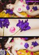 A naked woman laying on a bed of purple flowers.