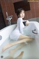 A woman in a white dress sitting in a bathtub.