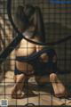 A woman sitting on the floor in a cage.